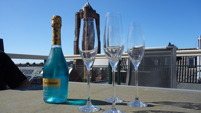 Šampanské a poháre na stopke, položené na stole na terase so skleneným zábradlím.jpg
